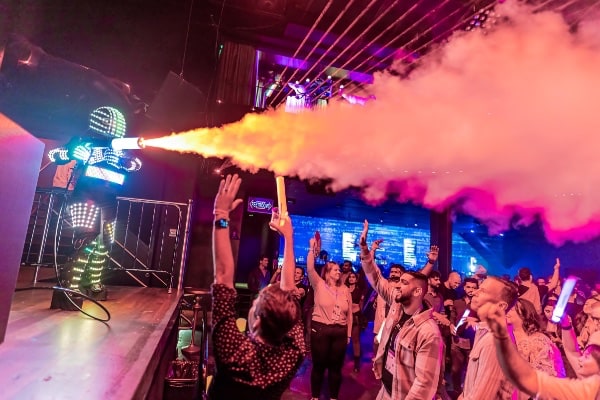 a group of people on a stage with a person holding a smoke gun
